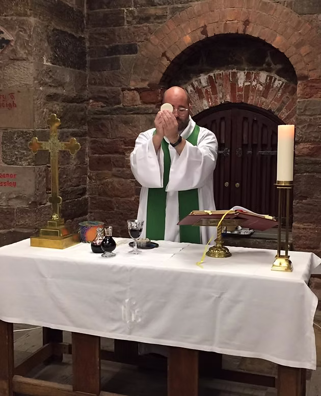 People walk under an arch toward the Dome of the Rock, with birds flying overhead and a cloudy sky in the background.
